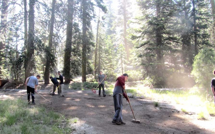 a group of outward bound students use tools to complete trail maintenance 